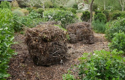 Compost stacks with wire holding the weeds in